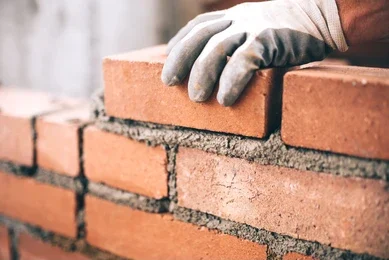 mason holding a brick in the process of bricking up a window