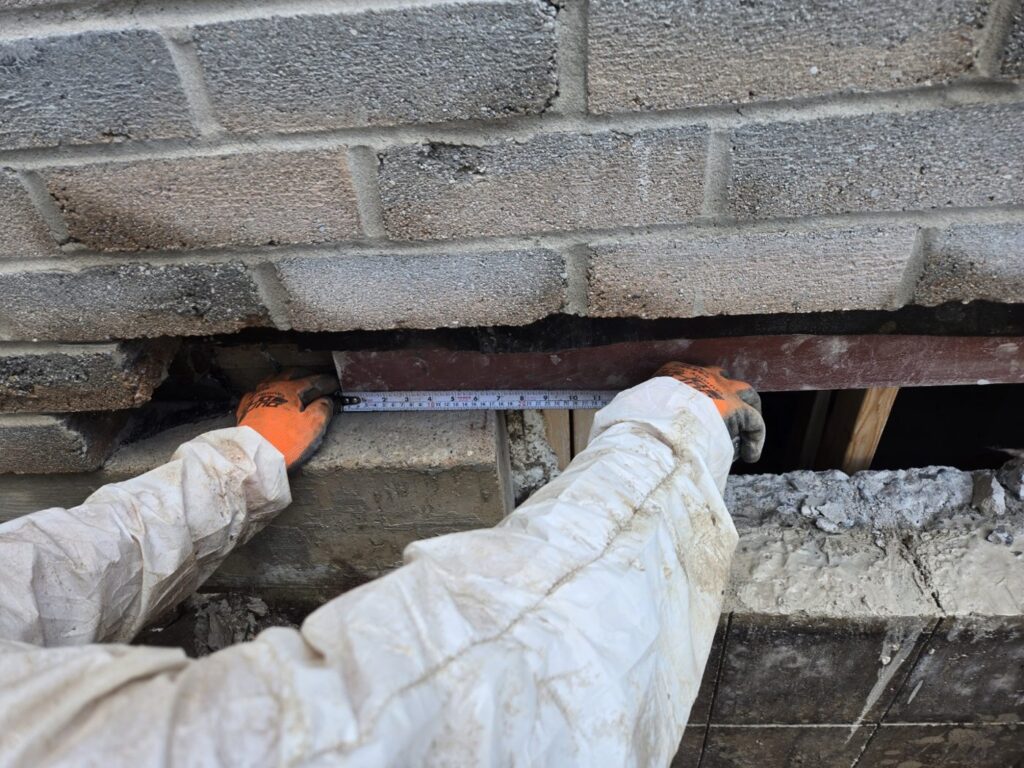Steel lintel being set above a new egress opening in a block foundation, Burlington